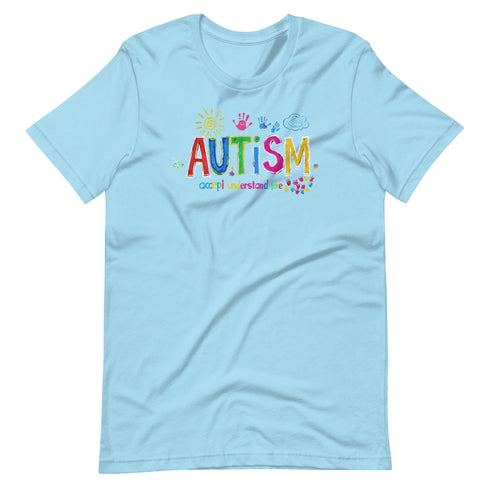 A light blue t-shirt with a colorful autism awareness design. "Autism" is surrounded by colorful, childlike drawings with "accept understand love" underneath.