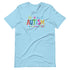 A light blue t-shirt with a colorful autism awareness design. "Autism" is surrounded by colorful, childlike drawings with "accept understand love" underneath.