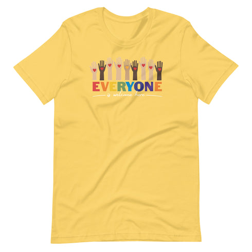 A yellow t-shirt with a colorful "Everyone is welcome here" design. Above the phrase, multicultural hands are shown with hearts on them.